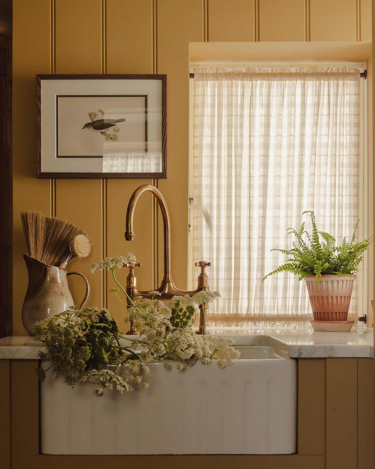 Double rod pocket café curtain in Elva cotton check, on brass poles top and bottom in a utility room at Baywell Studio