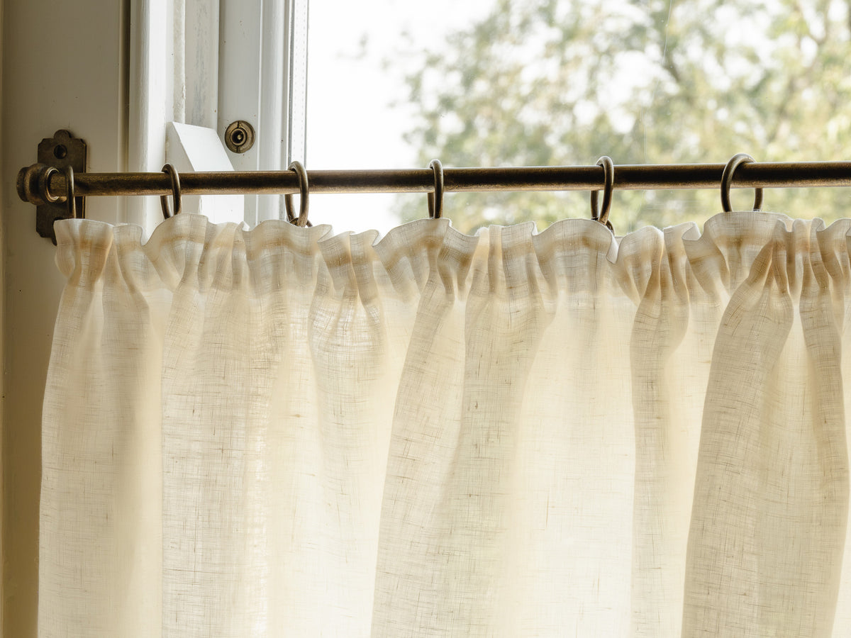 Close-up pleated café curtain in cream Sera linen on brass rings and pole, in a bright hallway at Baywell Studio