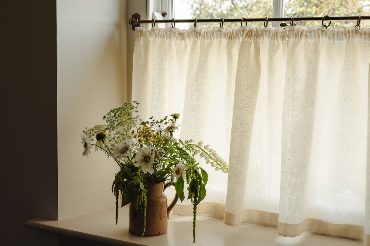 Close-up pleated café curtain in cream Sera linen on brass rings and pole, in a bright hallway at Baywell Studio