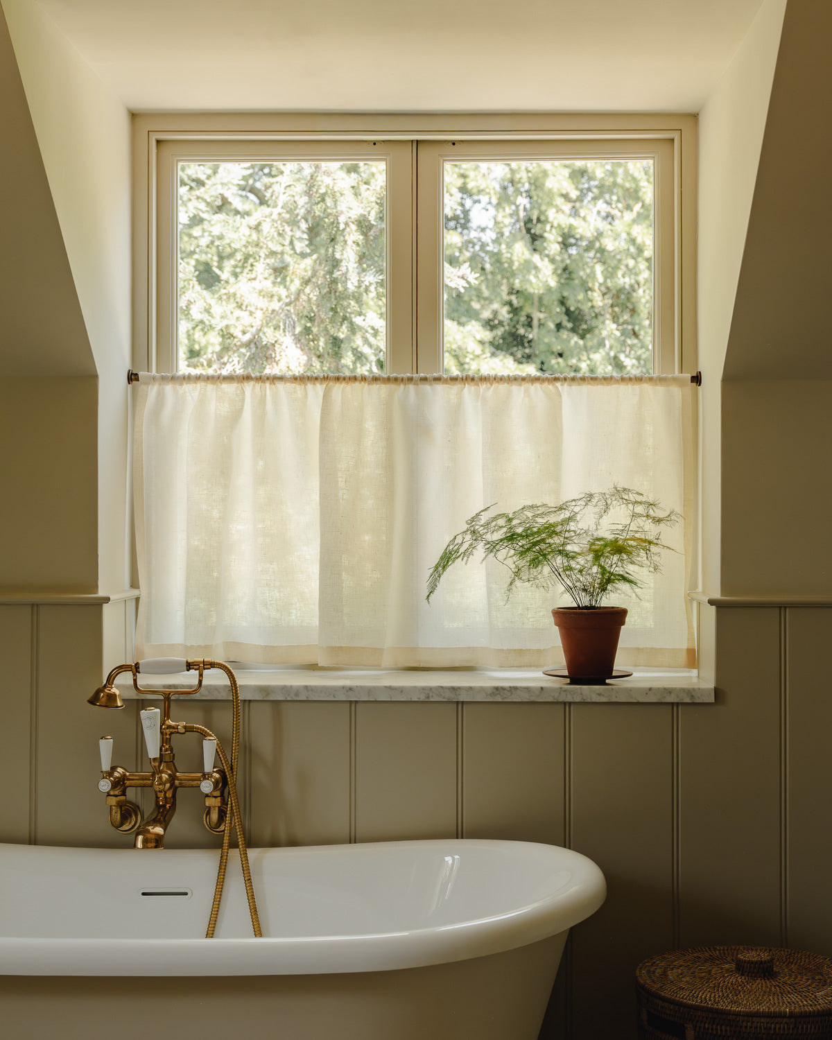 Rod pocket café curtains in cream Sera linen on a brass pole, for bathroom privacy above a roll-top bath at Baywell Studio