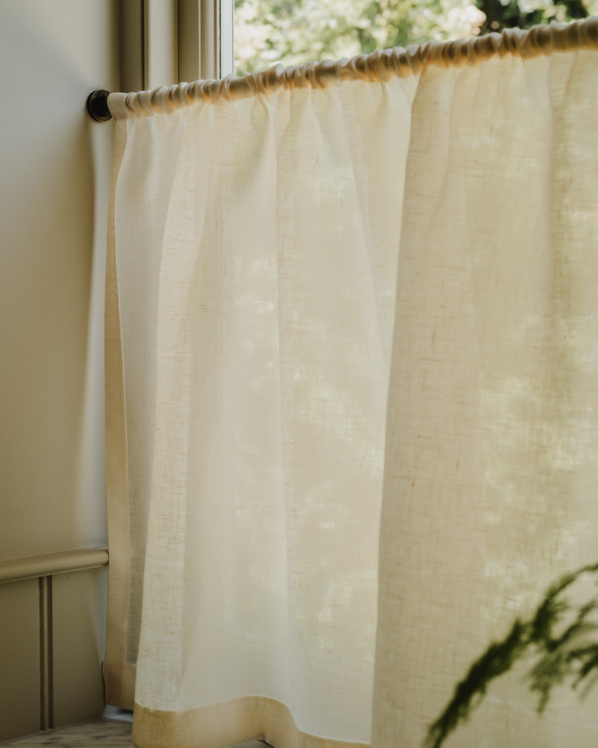 Rod pocket café curtains in cream Sera linen on a brass pole, for bathroom privacy above a roll-top bath at Baywell Studio