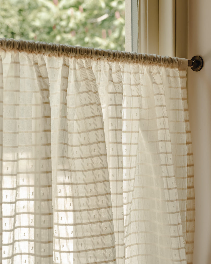 Close-up rod pocket café curtain in Alda, an cotton fine weave, gathered on a slim brass pole in the cottage kitchen at Baywell Studio