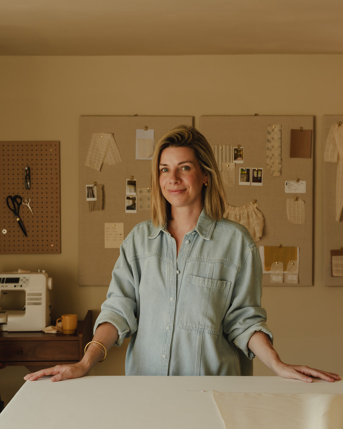 Sarah-Jane Santos, founder of Baywell Studio, at her worktable in the Charlbury studio, moodboards behind her