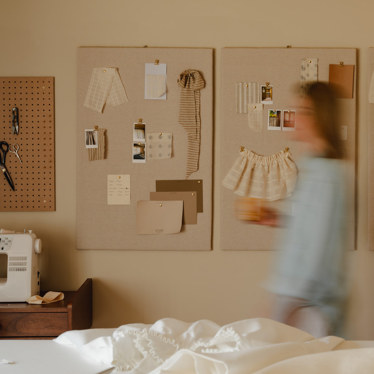 Sarah-Jane Santos at work in the Baywell Studio, Charlbury, passing linen moodboards of café curtain fabric swatches, sewing machine nearby
